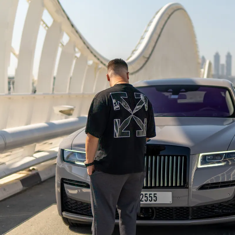 Dennis Loos von hinten, nachts neben seinem Rolls-Royce – der Blick geht auf die Straße