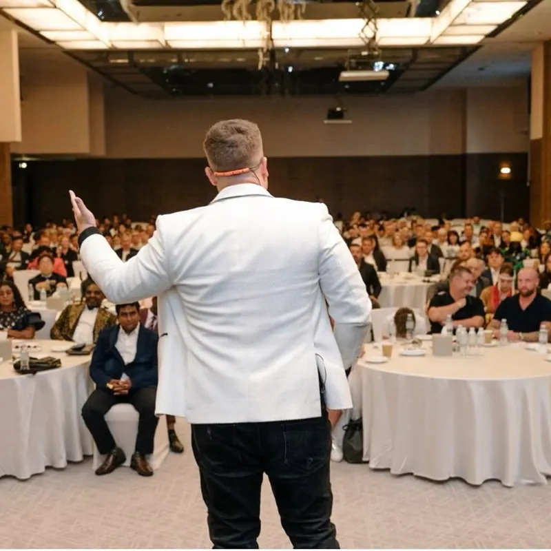 Dennis Loos spricht auf der Bühne vor einem vollen Saal